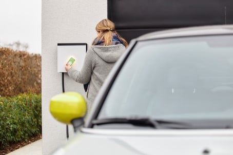Vrouw die haar auto thuis gaat opladen met haar Smappee EV Wall laadpaal. Ze gebruikt haar laadpas om zich te identificiëren.